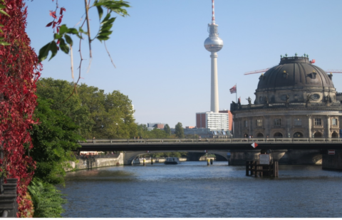 Picture of Berlin museum and TV tower from the river, with red vine leaves on the left