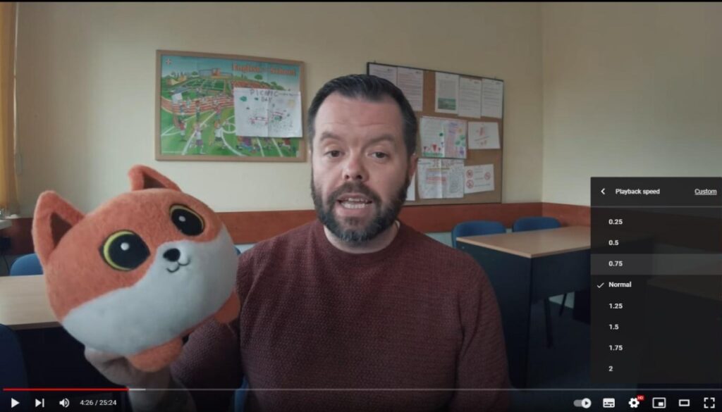 A still from a YouTube video showing the author holding a cute toy fox. A menu is open in the YouTube player showing a variety of different playback speeds to choose from, in case you need a slower speed to be sure what the fox says.